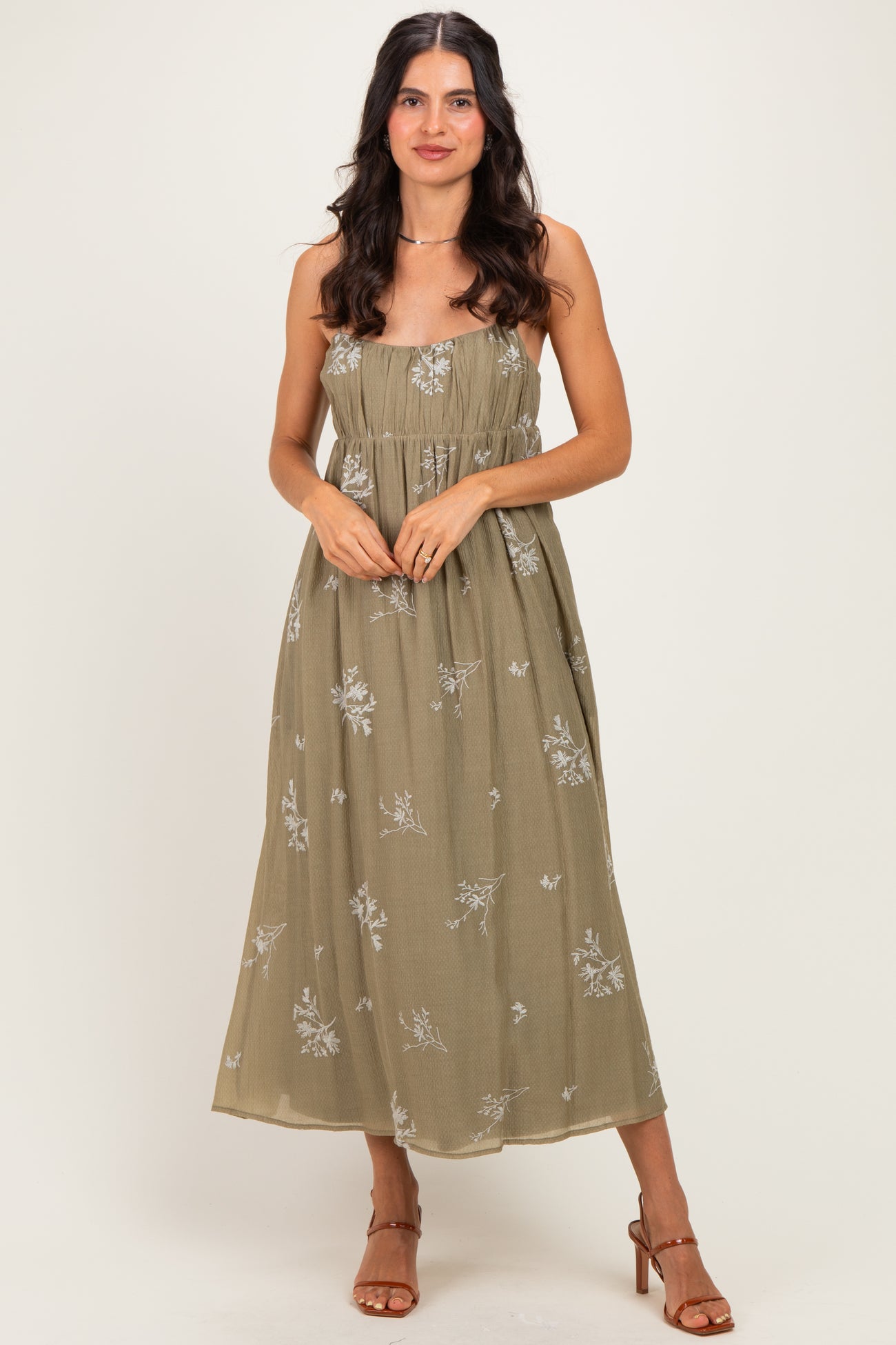 woman wearing a khaki floral strapless maxi dress with a flowy skirt and a fitted bodice