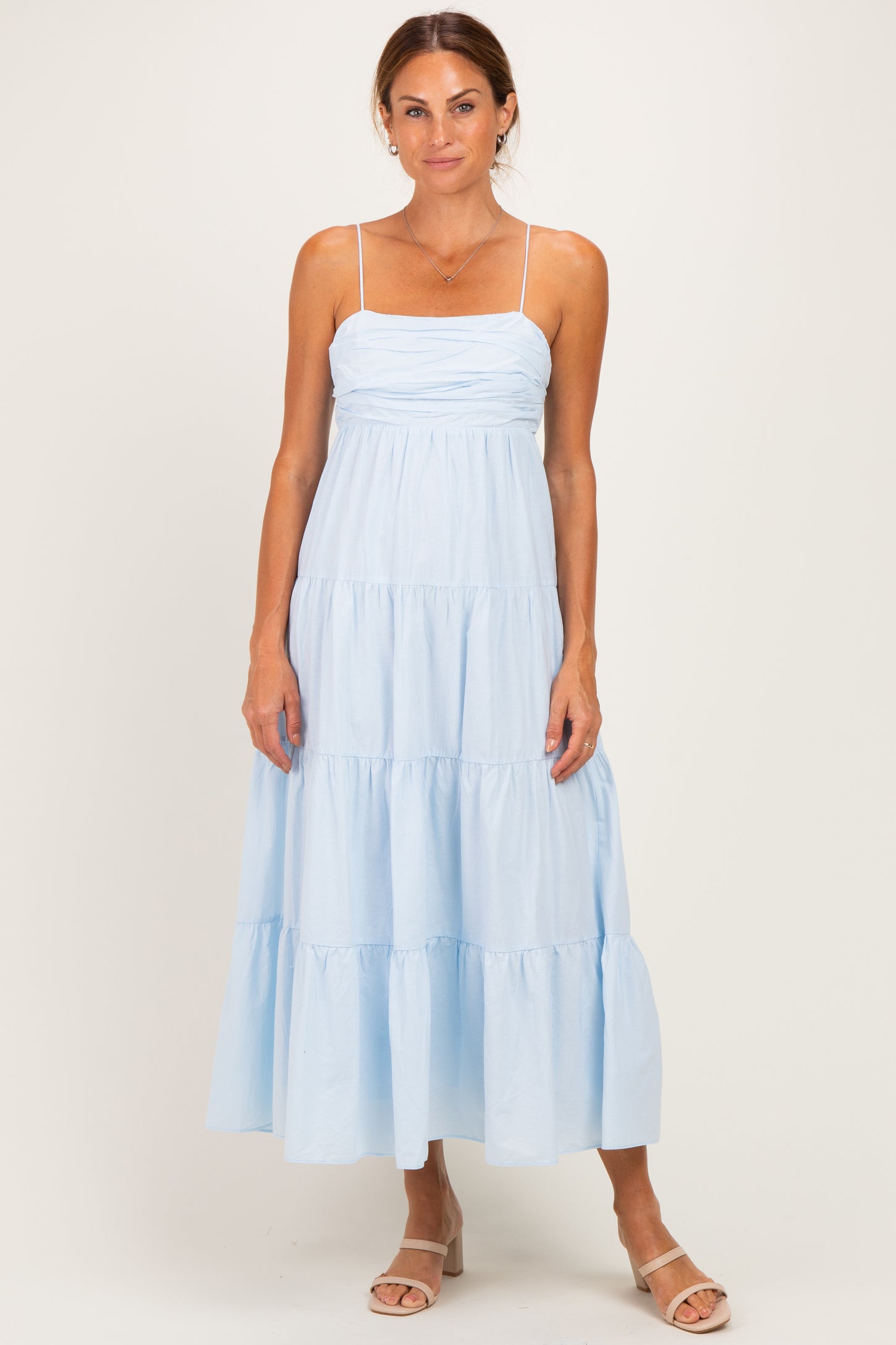 woman wearing a light blue tiered maxi dress with adjustable spaghetti straps and a fitted bodice