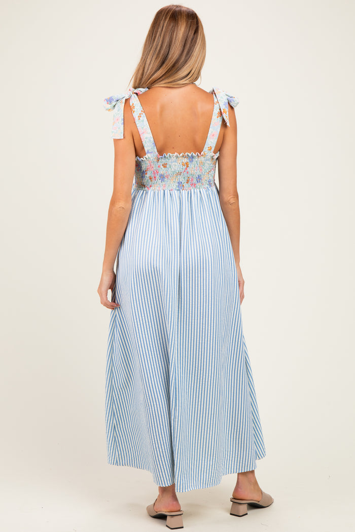 woman wearing a blue and white striped maternity maxi dress with floral smocked bodice and tie straps
