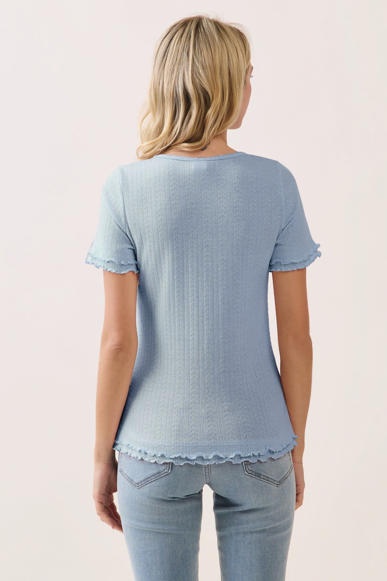 woman wearing a light blue short sleeve top with ruffled edges, styled with light blue jeans