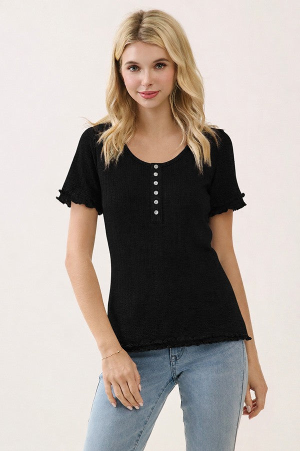 woman wearing a black short sleeve top with buttons and ruffle details, paired with light blue jeans