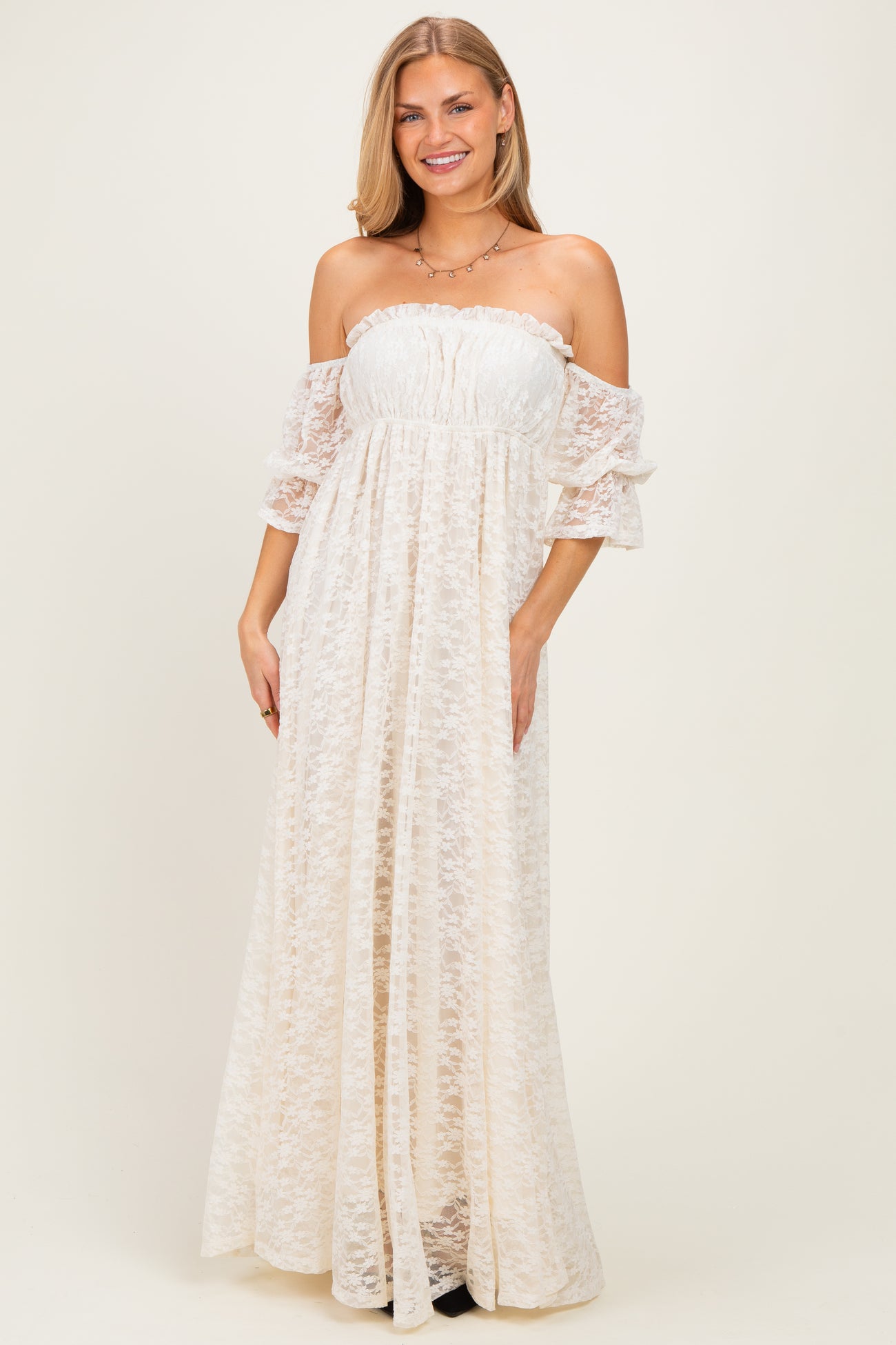 woman wearing an off-the-shoulder white lace maxi dress with puff sleeves and a gathered bodice
