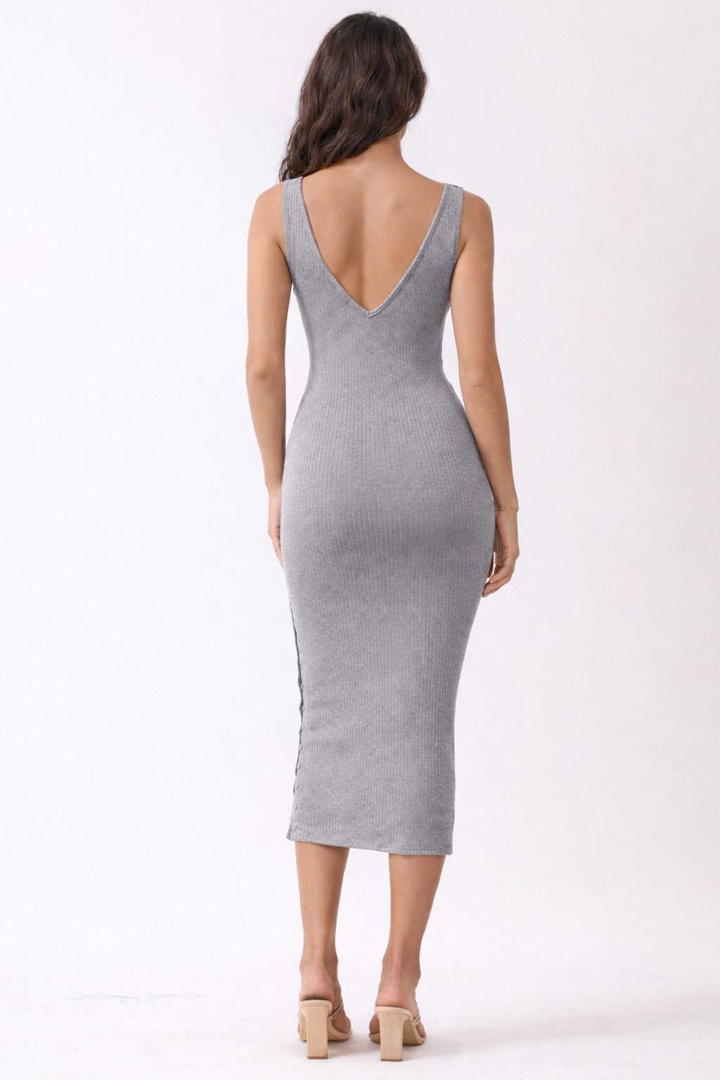 woman wearing a form-fitting gray ribbed midi dress with a deep V back and a slit on the side