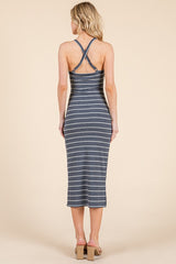 woman wearing a blue and white striped midi dress with crisscross back straps and a fitted silhouette