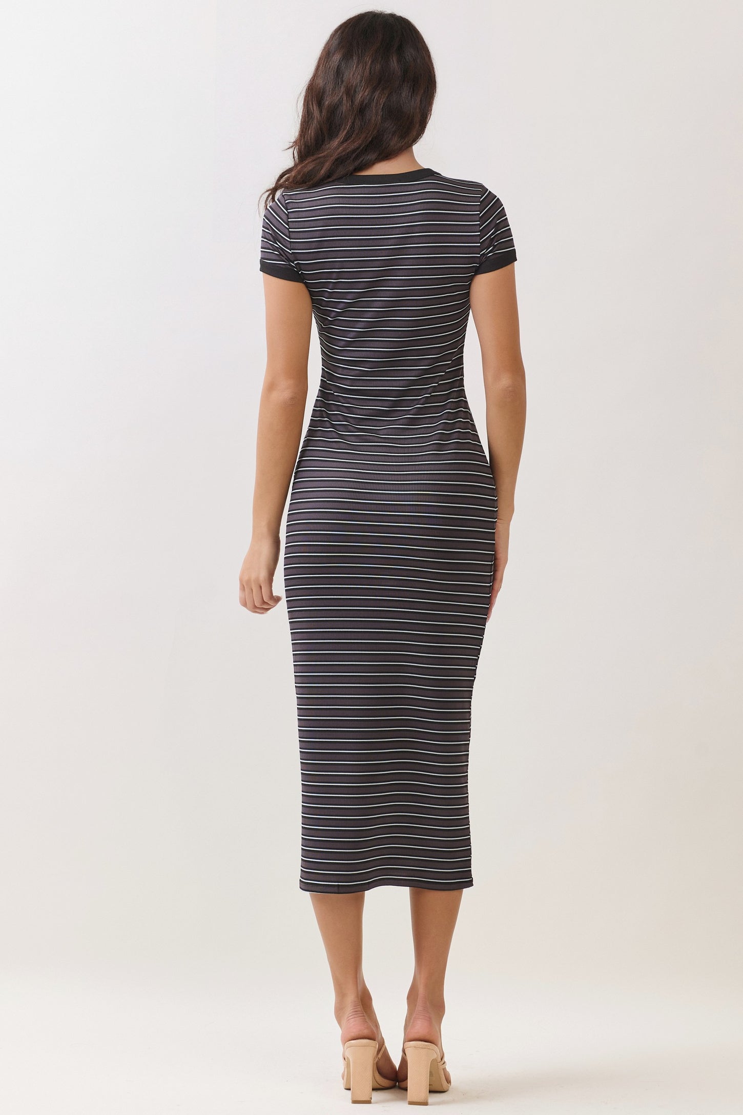 woman wearing a black and white striped midi dress with short sleeves, viewed from the back