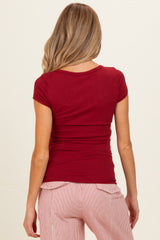 woman wearing a red short sleeve maternity top, shown from the back, paired with striped maternity pants