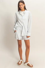 woman wearing a white and light blue striped oversized shirt and matching shorts with flip-flops