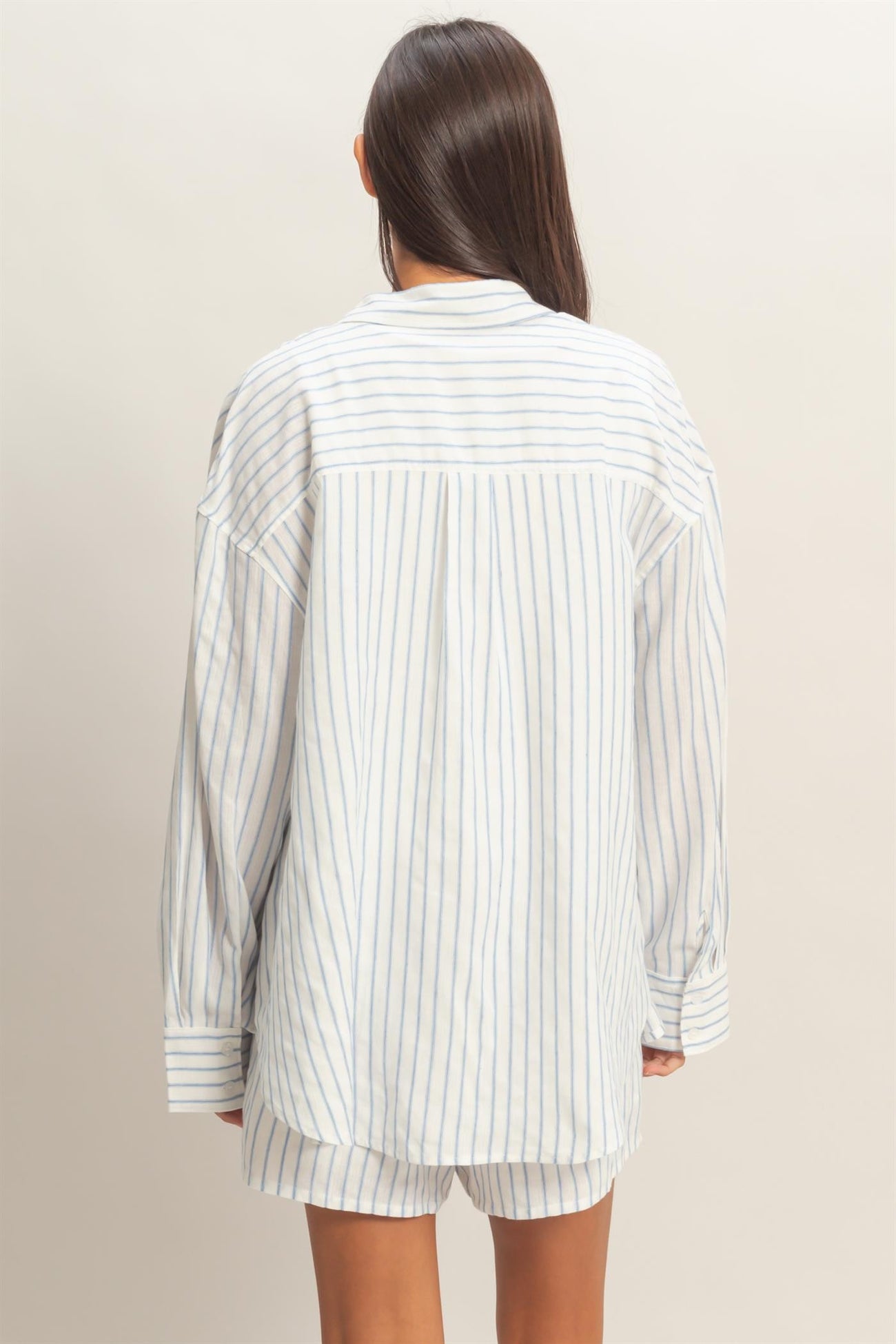 woman wearing a white and light blue striped oversized shirt, viewed from the back