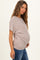 woman wearing a beige maternity top with a relaxed fit, showcasing her baby bump while wearing blue jeans