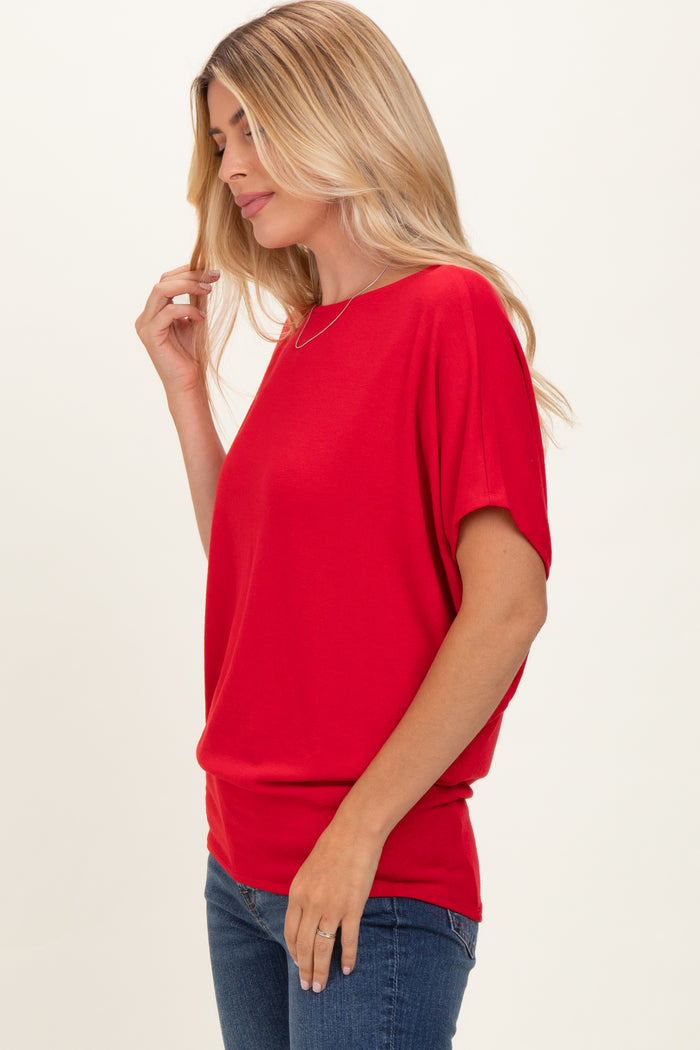 woman wearing a red short sleeve top with a relaxed fit and scoop neckline, paired with blue jeans