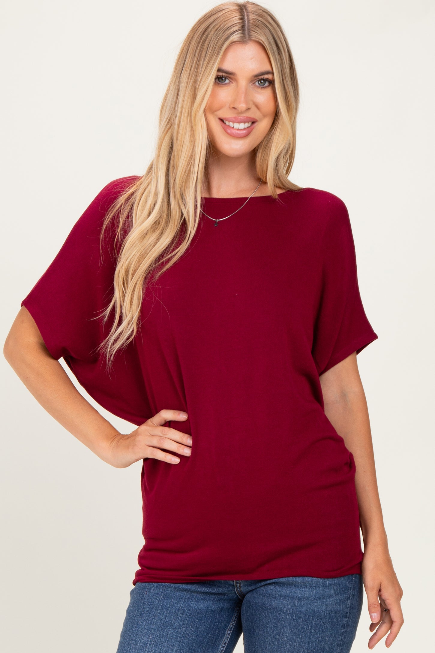 woman wearing a burgundy oversized tee with short sleeves and a relaxed fit, paired with blue jeans