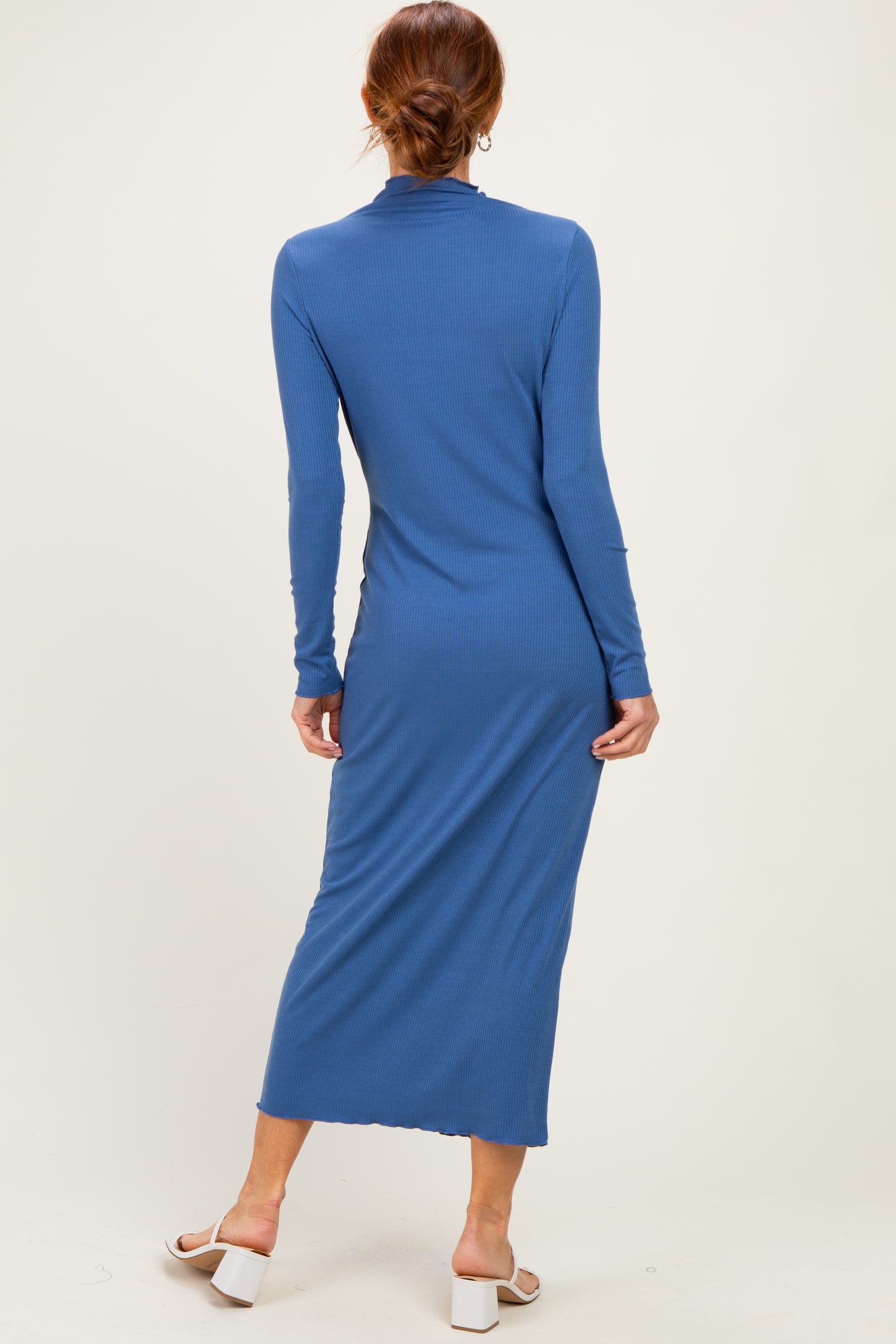 woman wearing a long sleeve blue midi dress with a fitted silhouette and back slit