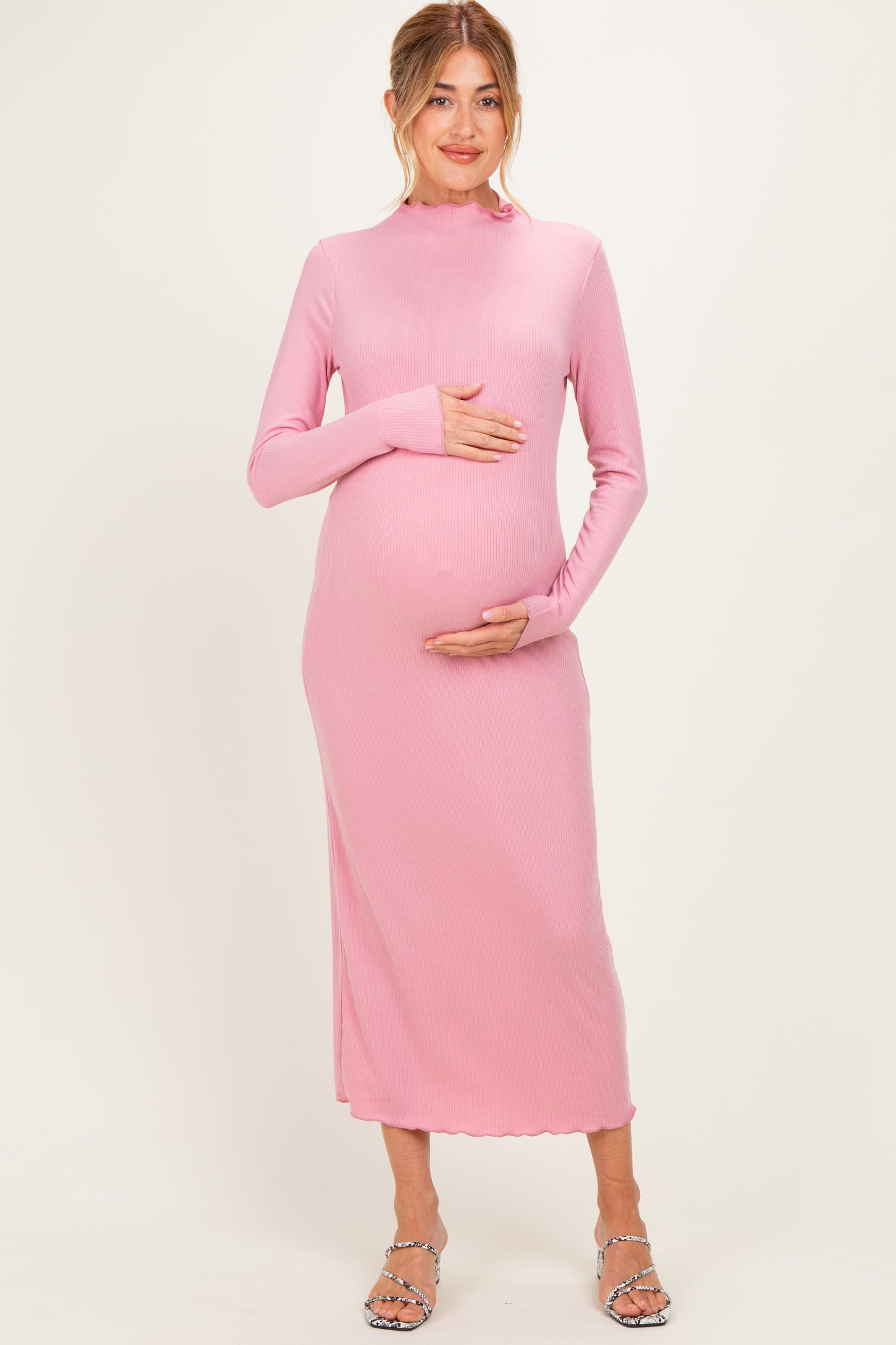 woman wearing a pink long sleeve ribbed maternity dress and holding her baby bump