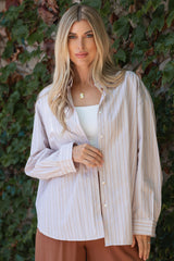 woman wearing a cream and light pink striped oversized button-up shirt with long sleeves and a v-neck top underneath