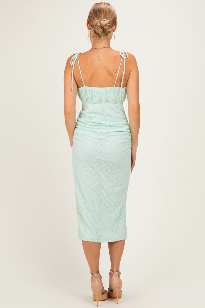 woman wearing a mint green fitted midi dress with lace detailing and adjustable tie straps, seen from the back