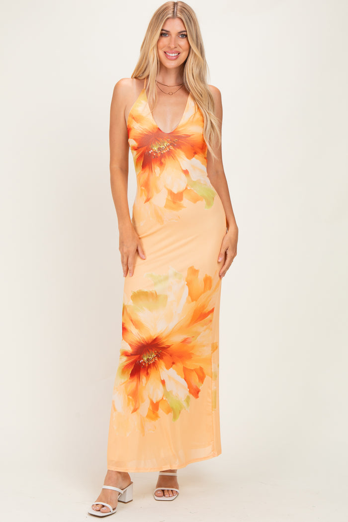 woman wearing an orange floral maxi dress with a deep V-neckline and spaghetti straps