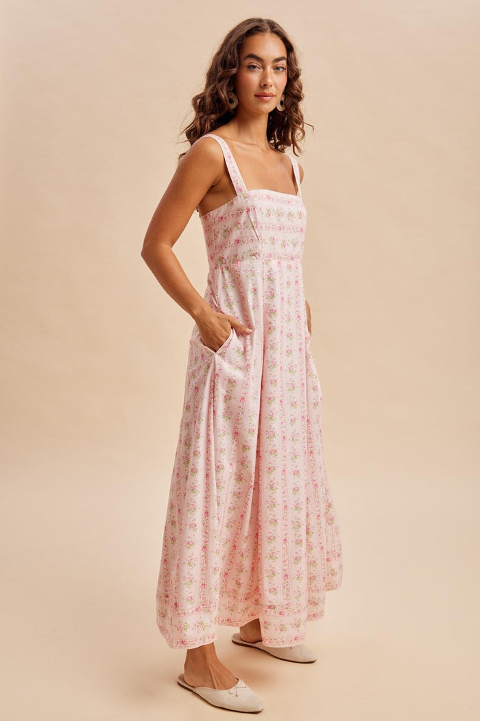 woman wearing a flowy pink floral maxi dress with slim straps and side pockets
