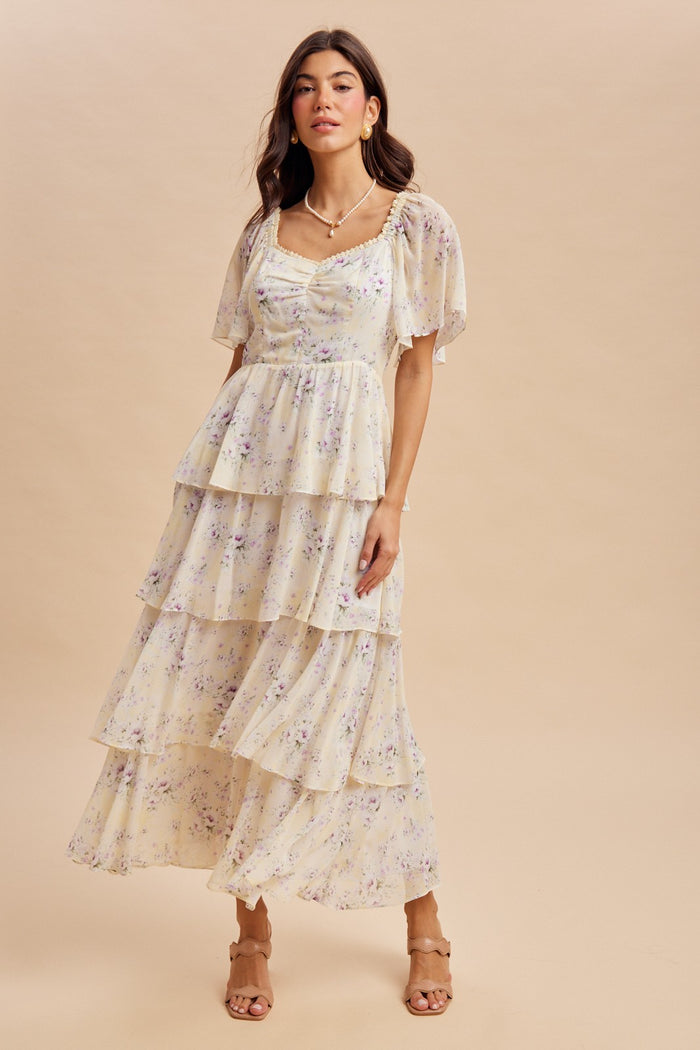 woman wearing a pastel yellow tiered maxi dress with floral print and puff sleeves