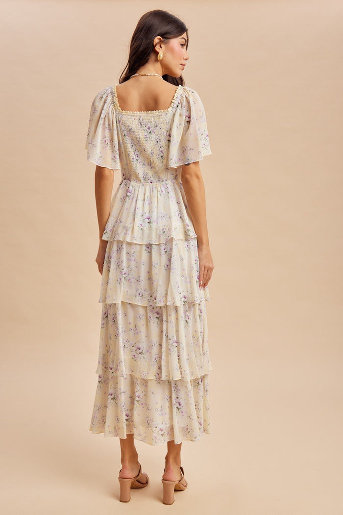 woman wearing a cream floral tiered maxi dress with puff sleeves, shown from the back