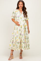 woman wearing a floral printed maternity dress with a tie waist and tiered ruffle hem, showing her baby bump