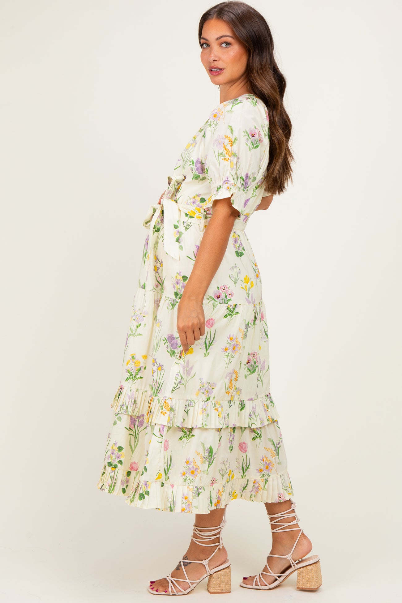 woman wearing a floral maternity dress with short sleeves and a tiered skirt, showing her baby bump