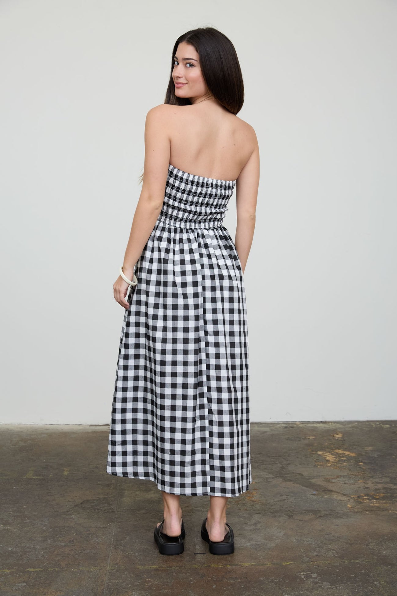 woman wearing a black and white checkered strapless maxi dress, showing the back view