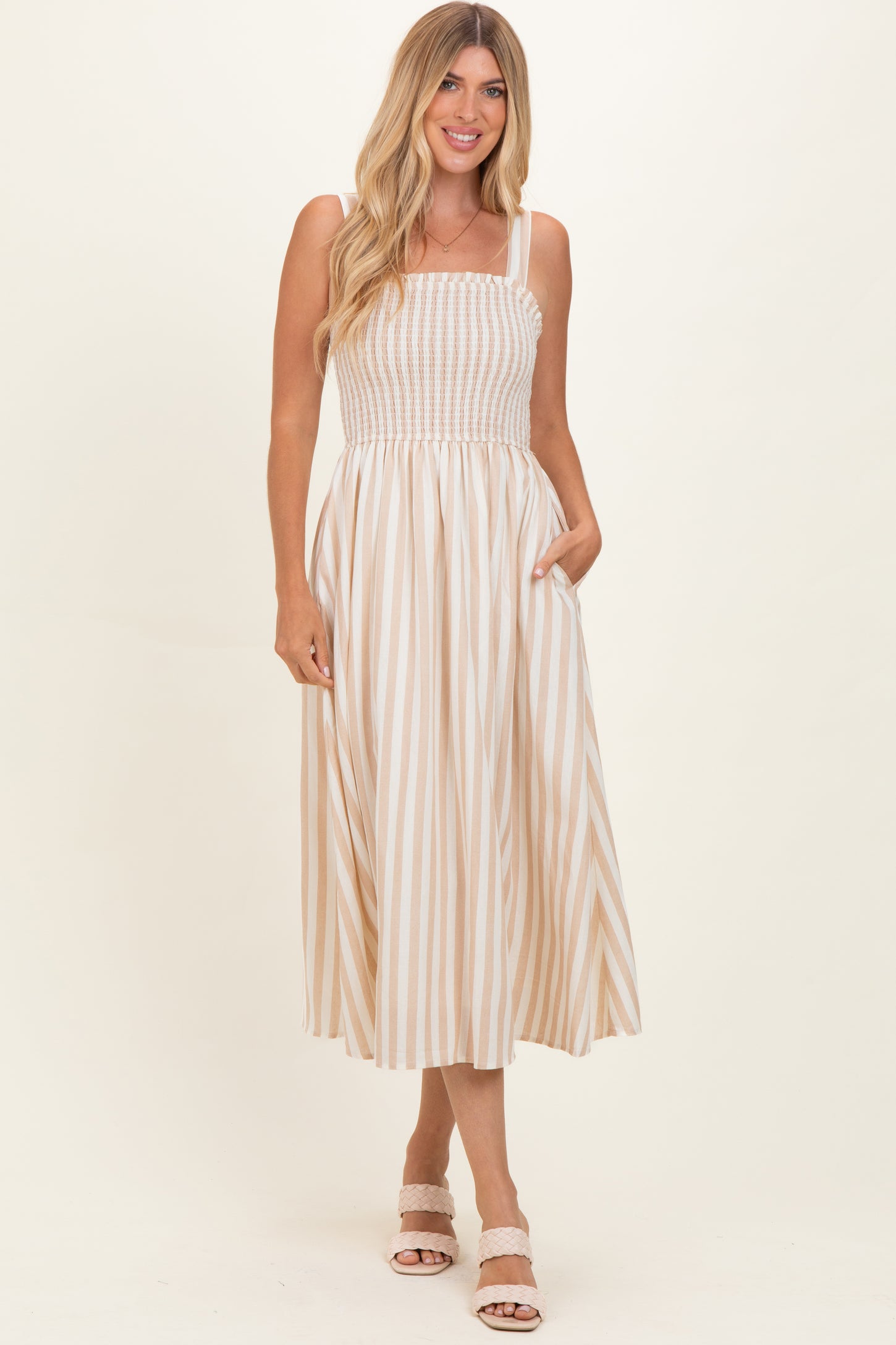 woman wearing a beige and white striped maxi dress with a smocked bodice and pockets
