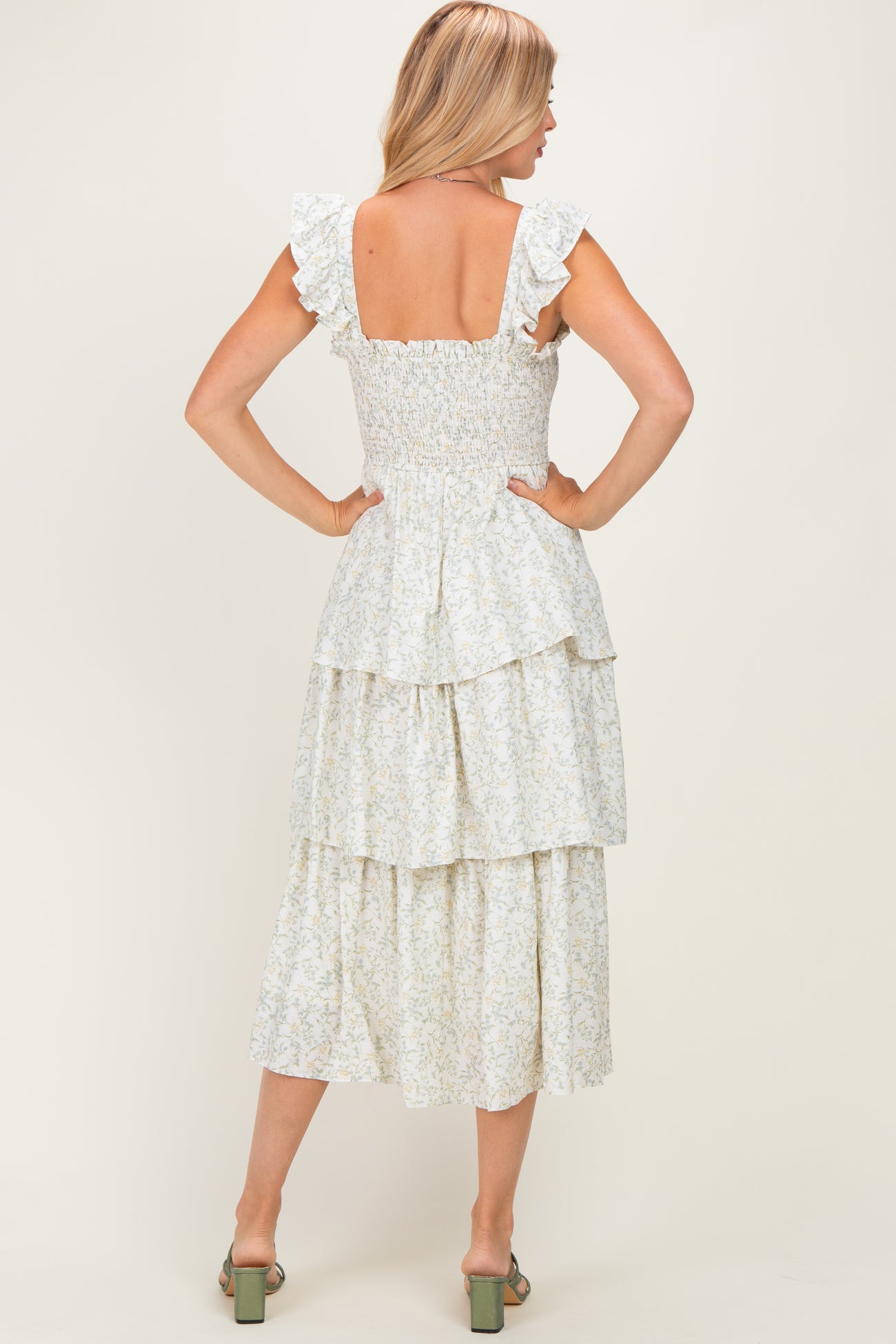woman wearing a floral print tiered midi dress with ruffled sleeves and a smocked bodice, shown from the back