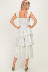 woman wearing a floral print tiered midi dress with ruffled sleeves and a smocked bodice, shown from the back
