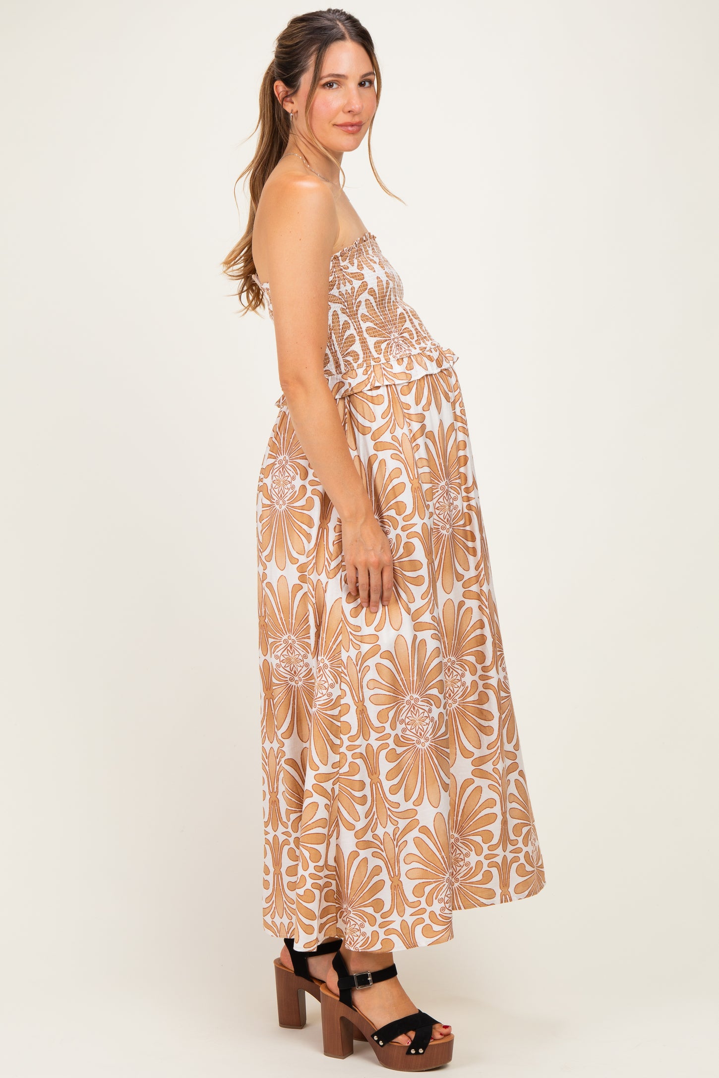 woman wearing a beige floral maternity maxi dress with a ruffled top and a visible baby bump