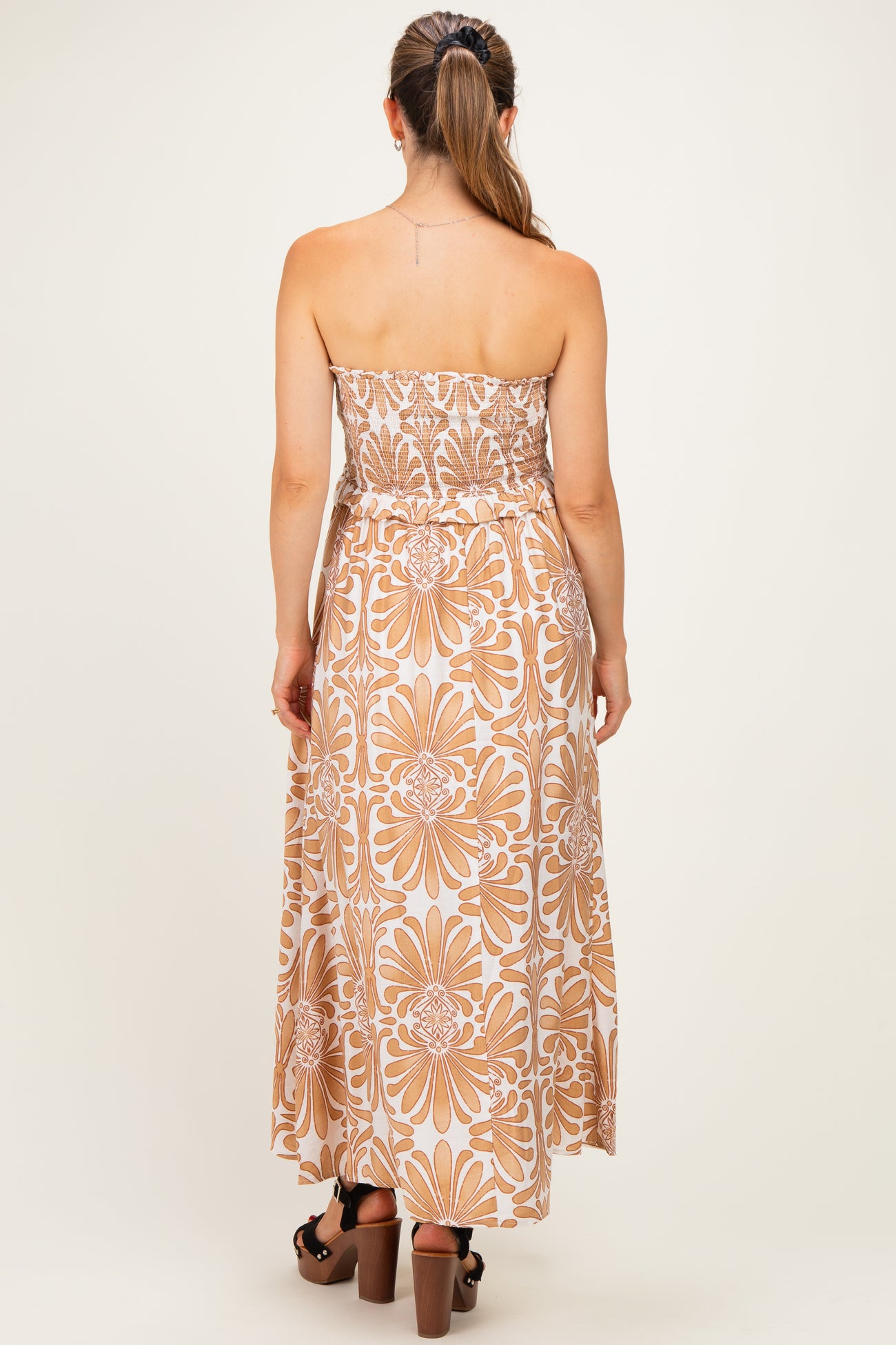 woman wearing a strapless floral print maternity maxi dress with a fitted bodice and flowy skirt