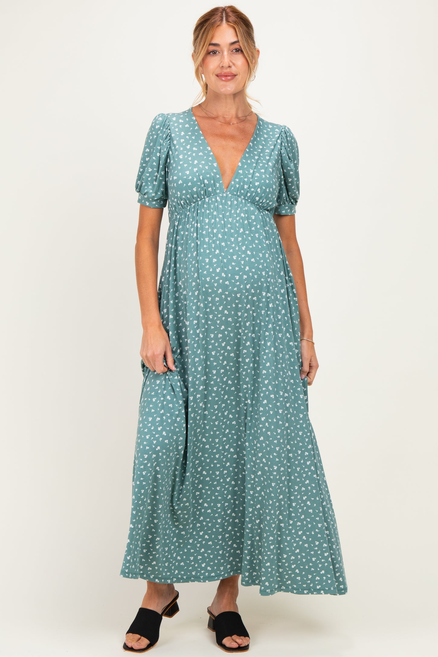 woman wearing a teal maternity dress with a v-neck and puff sleeves, showing her baby bump