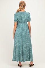 woman wearing a green maternity maxi dress with short puff sleeves and white floral print, showing a relaxed fit from the back