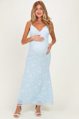 woman wearing a light blue floral maternity maxi dress and holding her baby bump