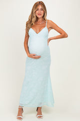woman wearing a light mint green floral maternity dress with spaghetti straps and a visible baby bump