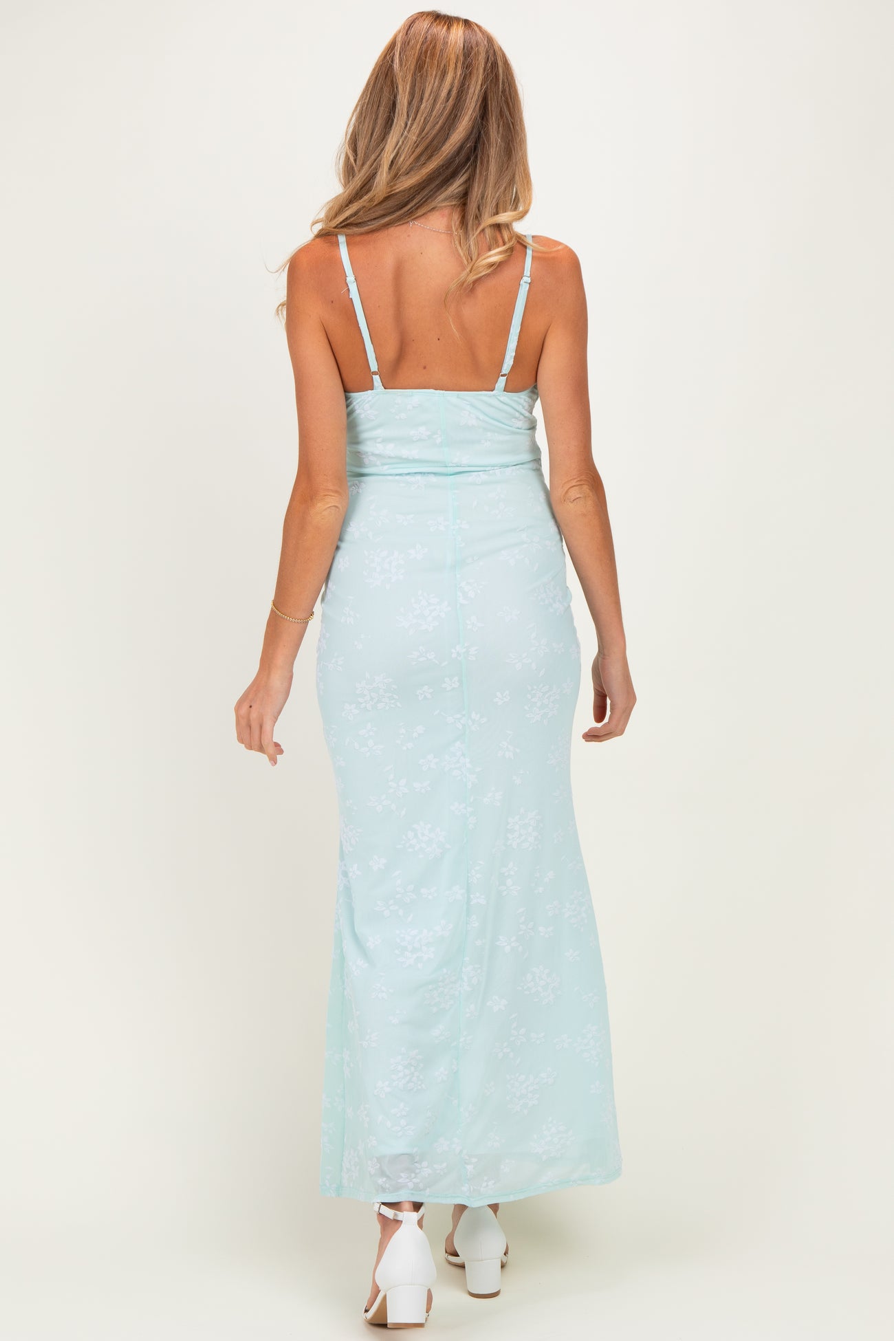 woman wearing a light blue floral maternity maxi dress with a fitted bodice and adjustable straps, showing a baby bump