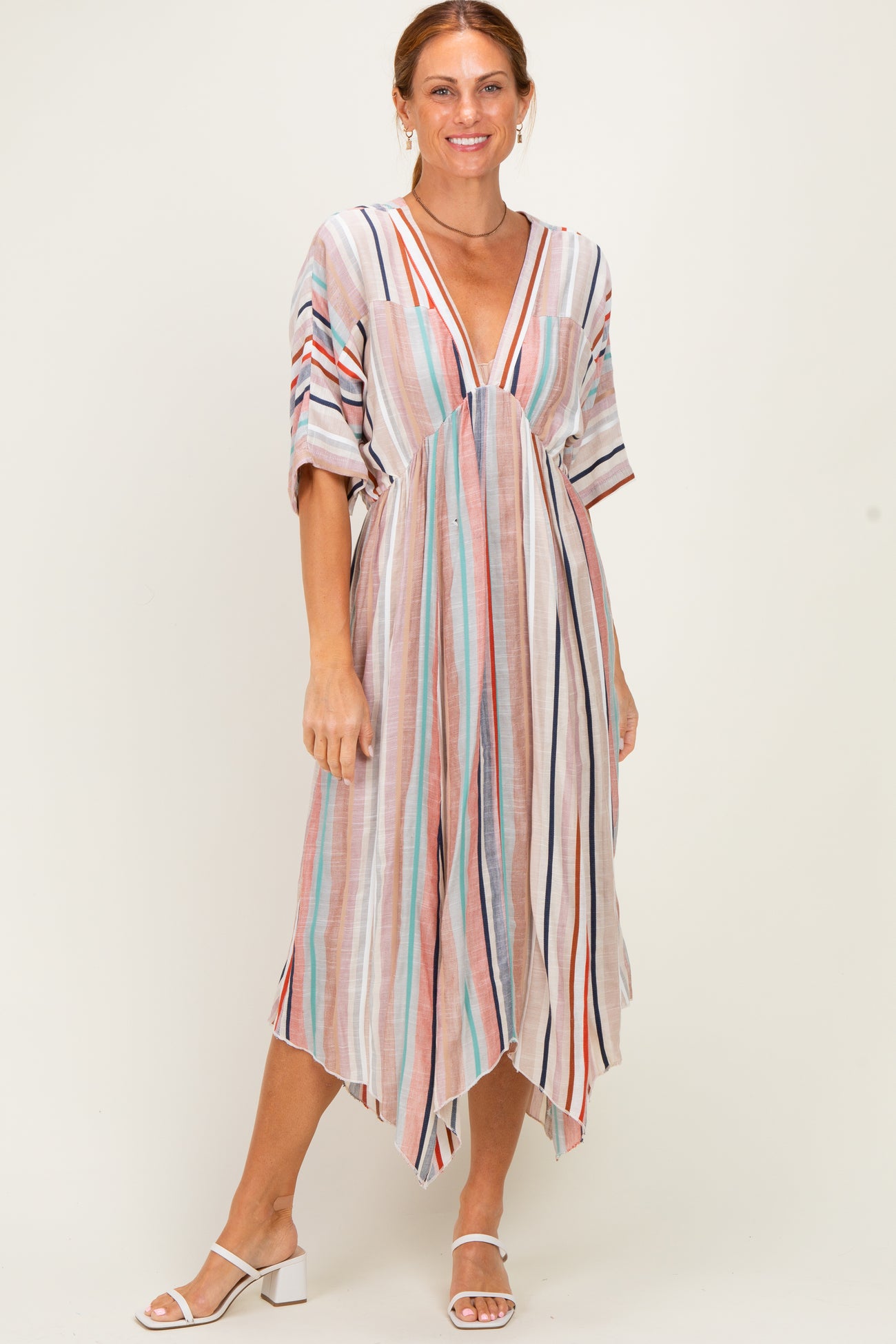 woman wearing a multi-striped maxi dress with a deep v-neck and short sleeves, standing and smiling