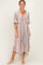 woman wearing a multi-striped maxi dress with a deep v-neck and short sleeves, standing and smiling