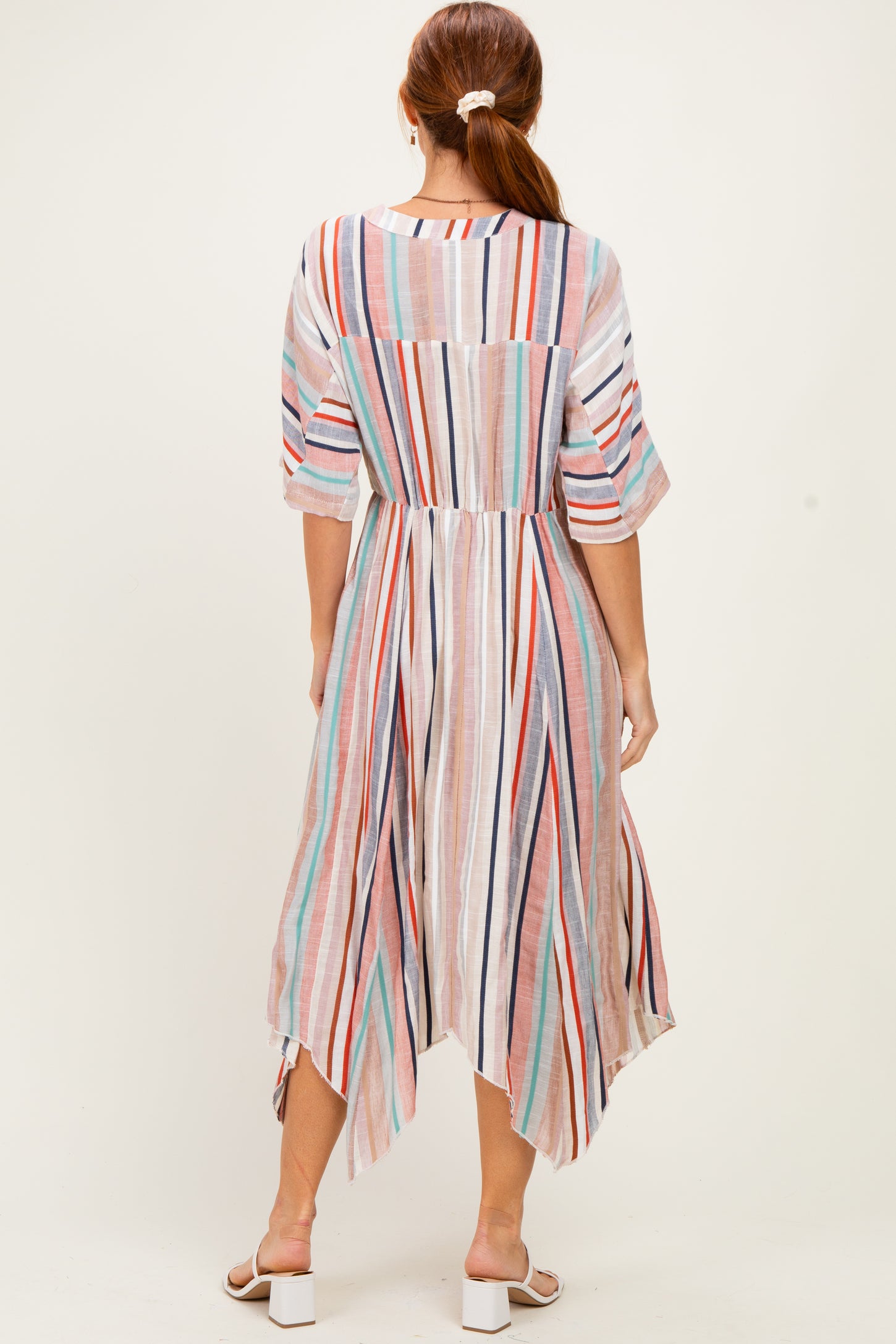 woman wearing a lightweight striped midi dress with a high-low hem and elbow-length sleeves, viewed from the back