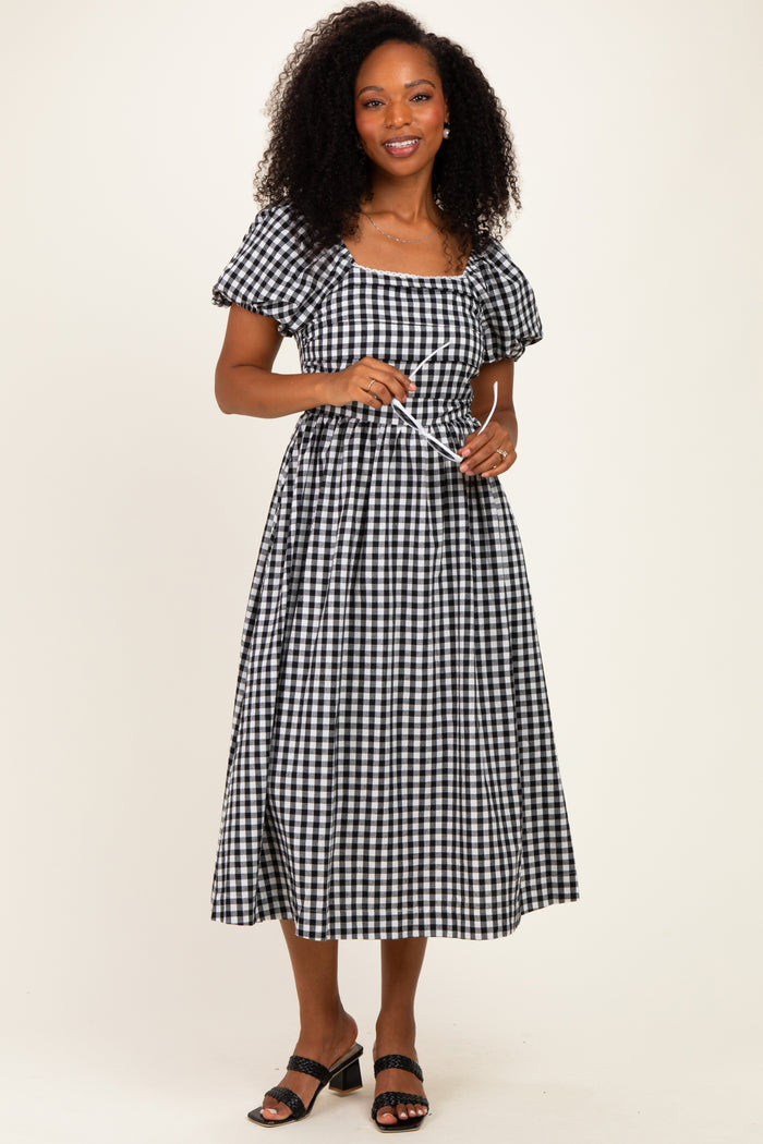 woman wearing a black and white gingham midi dress with puff sleeves and a tie waist detail