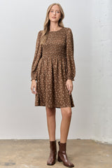 woman wearing a brown floral print smocked waist dress with long sleeves and ankle boots