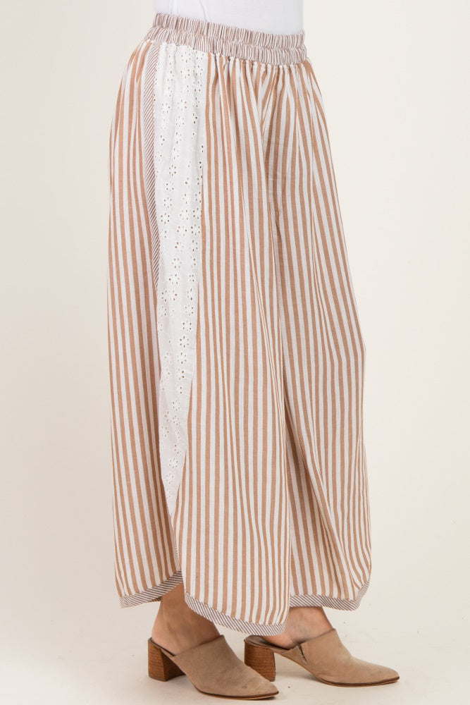 woman wearing a striped beige and white wide-leg pant with eyelet detailing on the side