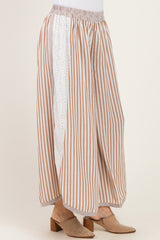 woman wearing a striped beige and white wide-leg pant with eyelet detailing on the side