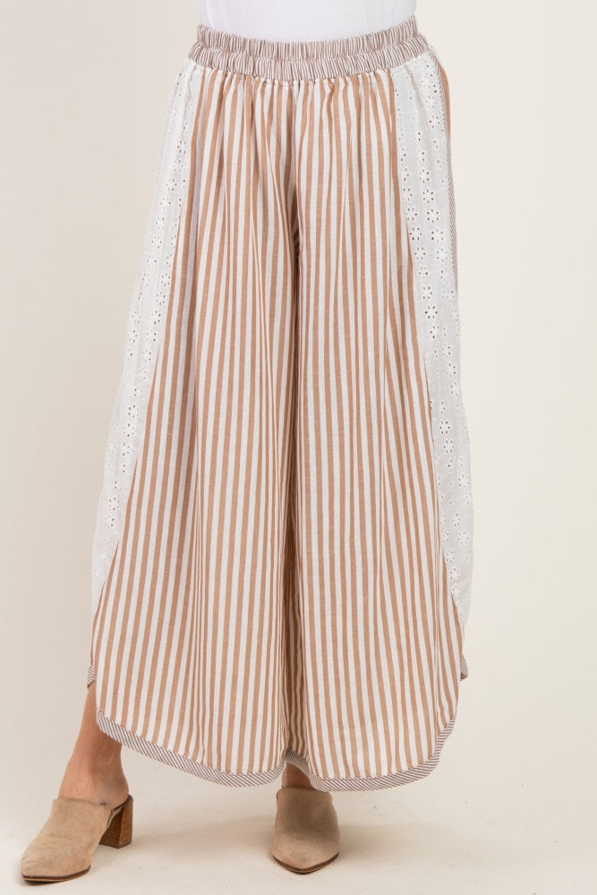 woman wearing beige and white striped wide-leg pants with eyelet lace detail on the sides