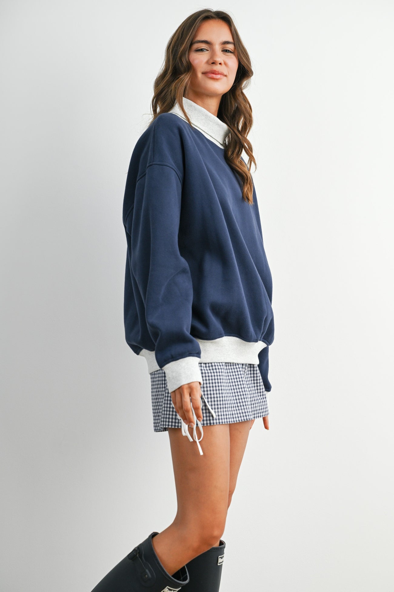 woman wearing a navy oversized sweatshirt with a white collar and a checkered mini skirt, styled casually