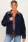 woman wearing a navy corduroy maternity jacket with a brown collar over a floral top and jeans