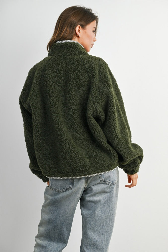 woman wearing a green oversized fleece jacket and light blue jeans, viewed from the back