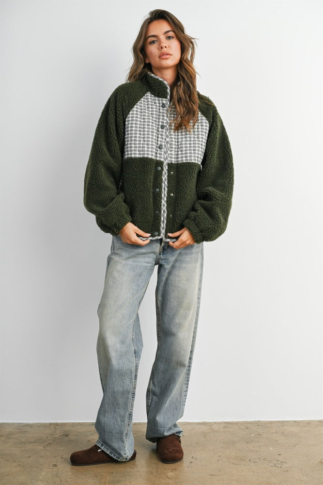 woman wearing an oversized green and gray fleece jacket with button details and light blue wide-leg jeans