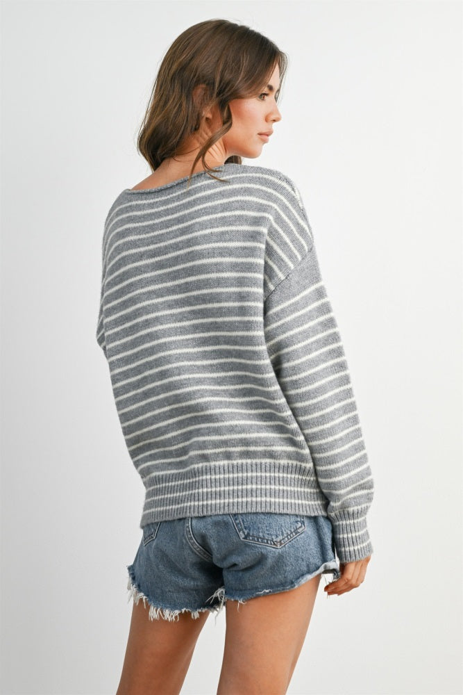 woman wearing a grey and white striped oversized sweater with a relaxed fit and distressed denim shorts