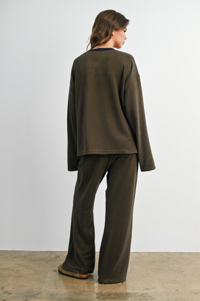 woman wearing a dark olive green long sleeve top and matching wide-leg pants, viewed from the back